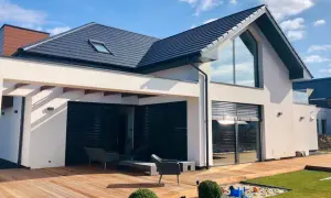 Nowoczesny dom z tarasem i dużymi oknami. Projekt domu 60m2 z drewnianym tarasem i piaskownicą dla dzieci.