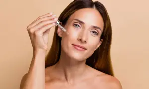 Donna applica un siero sul viso con un contagocce, un gesto essenziale per sapere come esfoliare la pelle e mantenerla luminosa.