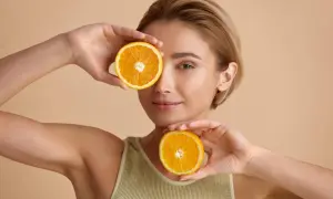 Kobieta z pomarańczami, symbolizującymi, co daje witamina C dla zdrowej skóry i blasku.