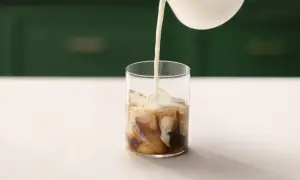 Mjölk hälls i ett glas med is och kaffe. Perfekt för ett enkelt iskaffe recept.