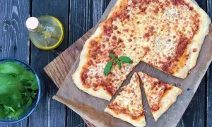 Pyszna pizza waga, z chrupiącym ciastem i ciągnącym serem, obok świeża bazylia i oliwa.