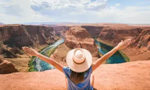 Kobieta w kapeluszu z rozłożonymi ramionami podziwia Horseshoe Bend. Ta co to jest? Niesamowity widok!