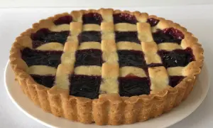 Una deliziosa crostata di marmellata con una griglia di pasta dorata e un ripieno scuro e invitante.