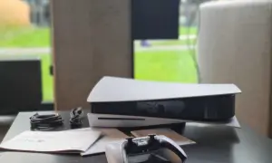 Konsola PlayStation 5 z kontrolerem i kablami na czarnym stole.