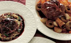 Stinco di maiale in pentola, tenero e succulento, servito con verdure e salsa scura.