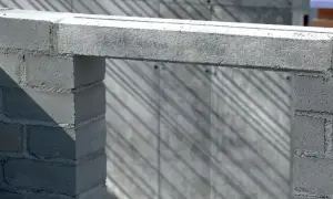 Betonowy nadproże nad otworem w budowie, podparty na bloczkach. Cienie na ścianie tworzą ciekawy wzór.