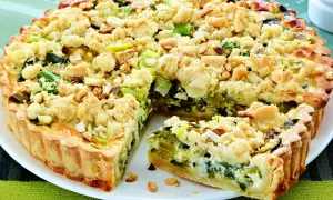 Ein herzhafter Kuchen mit Lauch und einer knusprigen Streuselhaube, auf einem weißen Teller serviert.