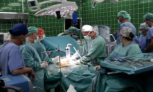 Zespół chirurgów w zielonych fartuchach i maseczkach podczas operacji.