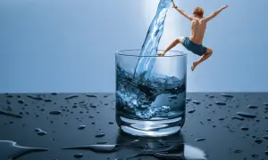 Chłopiec skacze do szklanki z wodą, jakby odkrywał, czym jest hydroterapia.