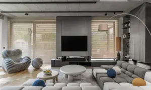 Nowoczesne, minimalistyczne wnętrza z szarą sofą, designerskim fotelem i betonowym sufitem.