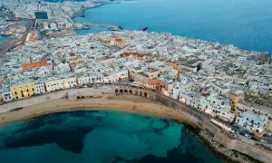 Gallipoli vecchia: un labirinto di vicoli bianchi che si affacciano sul mare turchese, con un'antica muraglia che abbraccia la costa.