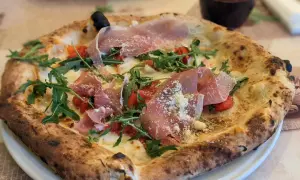 Eine köstliche Pizza mit Prosciutto, Rucola und Tomaten, die aussieht wie die beste Pizza Neapels.