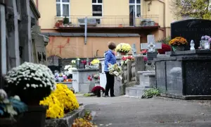 Kobieta z kwiatami na cmentarzu. Warto wiedzieć, jak odszukać groby żołnierskie i miejsca pamięci narodowej, by oddać im cześć.