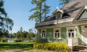 Zielony dworek z białymi zdobieniami, otoczony drzewami i jeziorem. Idealne miejsce na spokojny spacer i zapoznanie się z historią - białowieża plan zwiedzania.