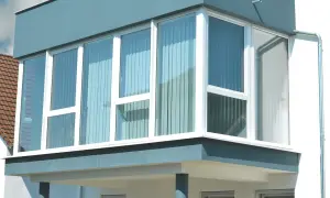 Moderner Anbau mit großen Fenstern, der einen Balkon zum Wintergarten umbauen lässt.