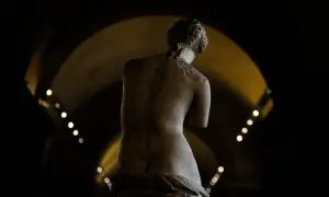 Statue de la déesse de l'amour, vue de dos, dans une lumière tamisée.