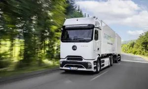 Un camion électrique Mercedes eActros GigaSpace roule sur une route bordée d'arbres.