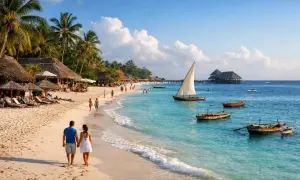 Zanzibar co warto zobaczyć: rajska plaża z palmami, łodzie na turkusowym morzu i spacerująca para. Idealne miejsce na wakacje.