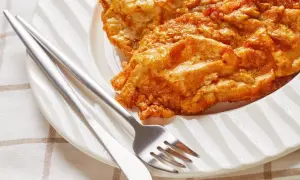 Złocisty kotlet słoneczny, chrupiący i apetyczny, czeka na talerzu z widelcem i nożem.