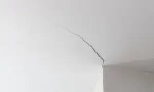 Fissure sur un plafond blanc, signe d'une trame de renovation nécessaire.