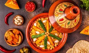 Un colorato cous cous marocco, con verdure, mandorle e albicocche secche, servito in una tajine decorata.