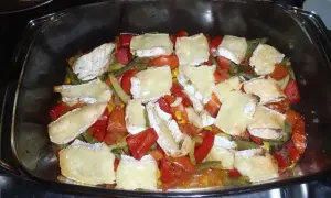 Zapiekanka z warzywami i kawałkami sera camembert w szklanym naczyniu.