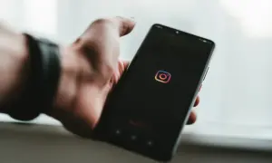 Dłoń trzyma smartfon z ikoną Instagrama. Dowiedz się, jak znaleźć zarchiwizowane posty na Instagramie, aby odzyskać stare wspomnienia.