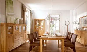 Elegancki salon w starym stylu aranżacje: drewniane meble, brązowe krzesła i stół nakryty do kolacji.