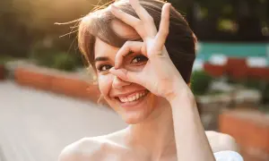 Uśmiechnięta kobieta z ręką przy oku, jakby szukała czegoś. To świetne mentalizacja przykłady, jak patrzeć na świat z ciekawością.