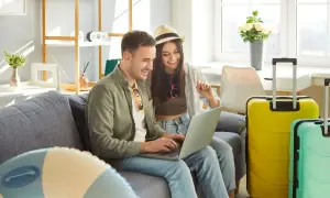Para planuje podróż, korzystając z laptopa, obok walizek.