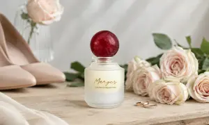 Eleganckie perfumy na ślub, obok róż i obrączek.