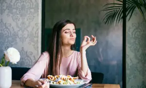 Frau genießt ihr Essen, als ob sie OMAD Fasten praktiziert und die einzige Mahlzeit des Tages zelebriert.