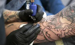Artysta w czarnych rękawiczkach tworzy na ramieniu skomplikowany wzór irezumi, dodając kolejne linie do smoka i fal.