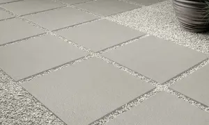 Posa a secco su ghiaia: lastre quadrate grigie alternate a ghiaietto bianco creano un percorso moderno e pulito.