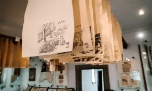 Rzędy ręcznie rysowanych scen na papierze czerpanym wiszą pod sufitem, tworząc unikalną galerię.