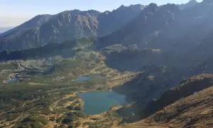 Widok na Tatry z licznymi stawami i kosodrzewiną. Szlak przez murowaniec prowadzi w kierunku górskich szczytów.