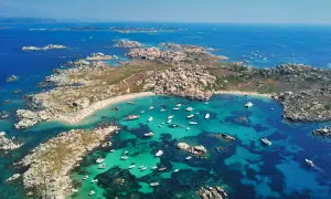 Vue aérienne d'une **excursion île Lavezzi** : eaux turquoise, plages de sable fin, rochers granitiques et nombreux bateaux au mouillage.