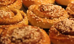 En närbild på nybakade kanelbullar, perfekta för kanelbullens dag. Strösslade med pärlsocker och kanel.