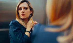 Kobieta narcyz poprawia włosy, patrząc w lustro. Jej spojrzenie jest intensywne, a makijaż podkreśla urodę.