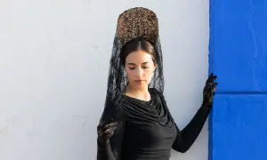 Mujer con peineta y mantilla negra, guantes de encaje, lista para una ocasión especial.
