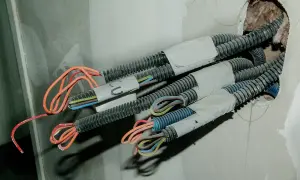 W ścianie widać wiązki przewodów w peszlach. Czy czerwony to plus, czy minus? Instalacja elektryczna w trakcie budowy.