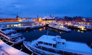 Schneebedeckte Schiffe im Hafen von Konstanz, beleuchtet vom Glanz des Weihnachtsmarktes.