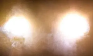 Deux halos lumineux, couleur feu de croisement, traversent une brume légère.