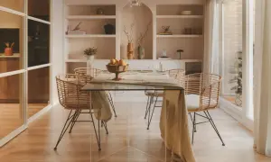Comedor moderno con mesa de cristal y sillas de ratán. Estanterías empotradas con decoración. El precio del proyecto de interiorismo se ajusta a este estilo.