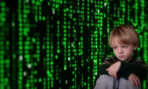 Smutny chłopiec na tle zielonego kodu. Jak zapobiegać cyberprzemocy? Edukacja i wsparcie to klucz do bezpieczeństwa w sieci.