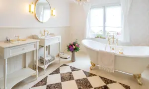 Elegancka łazienka w stylu angielskim z wolnostojącą wanną, złotymi bateriami i ozdobną podłogą.
