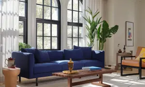 Granatowy salon inspiracje: nowoczesna sofa, drewniana ława, skórzany fotel i duże okna tworzą przytulną przestrzeń.