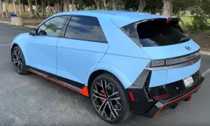 Niebieski Hyundai Ioniq 5 N z czarnymi akcentami i pomarańczowymi detalami stoi na parkingu.
