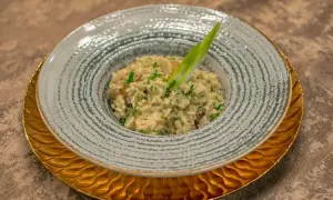 En krämig svamprisotto, kanske det godaste risotto receptet, serverad i en vacker skål med en grön garnityr.