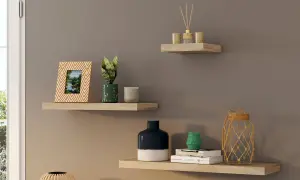 Trois étagères murales en bois clair décorées d'objets : cadre photo, plantes, bougies, vases, livres et diffuseur.